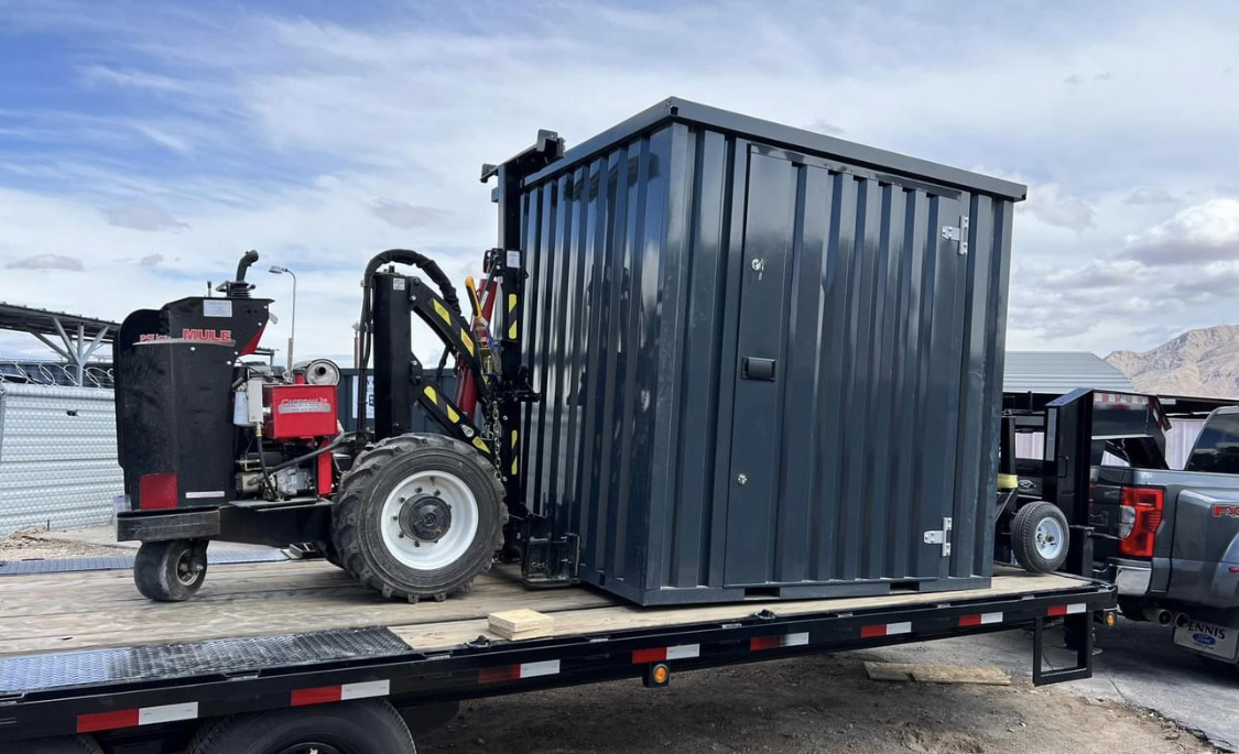 Longbox being placed by a portable forklift on a flatbed trailer